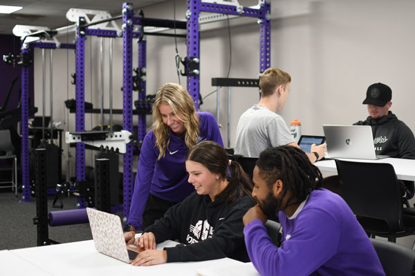 Students engaging with faculty member around table in the OIO Human Performance Lab